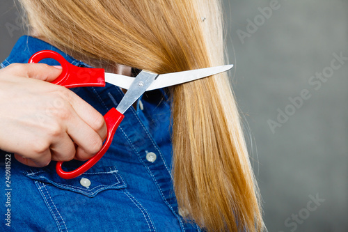Blonde woman cutting her hair.
