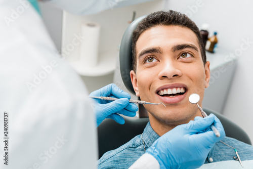 Canvas Print cheerful african american man with during examination in dental clinic