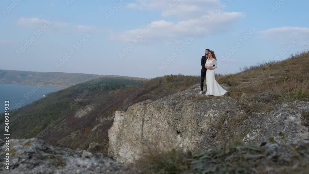 Newly married wedding couple stand near a cliff overlooking the sea. Newly married wedding couple stand near a cliff overlooking the sea.