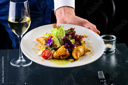Waiter serving tasty dishes at restaurant