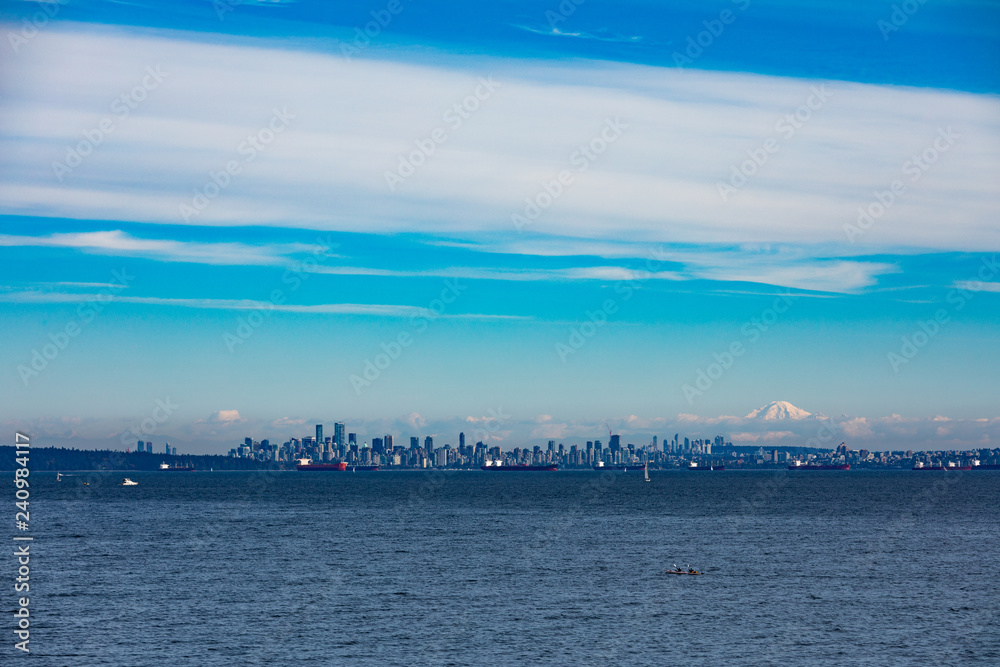 Vancouver City at the Western Canadian Pacific Ocean coast with oil tankers anchored in harbor and Mount Baker in the far distance shadowing the cityscape skyline, Biritish Columbia, BC, Canada
