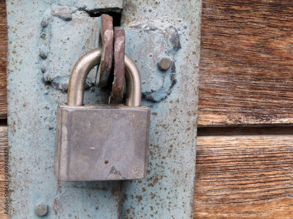 Padlock on wooden gates upholstered with iron. Locked doors, home security concept Padlock on wooden gates upholstered with iron. Locked doors, home security concept