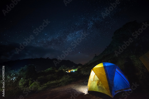 Glowing tent in the mountains under a starry sky