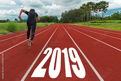 The start into the new year 2019. Start up of runner man running on race track go to Goal of Success, people running as part of Number 2019, copy space. Holiday Concept