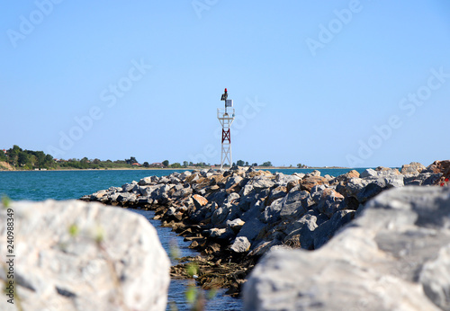 Lighthouse in Aegean Sea on rocks. 