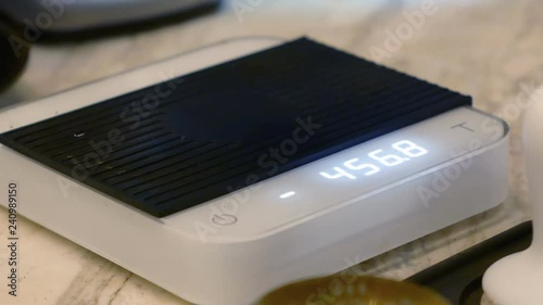 Barista controls grinding coffee in portafilter the amount on a scale