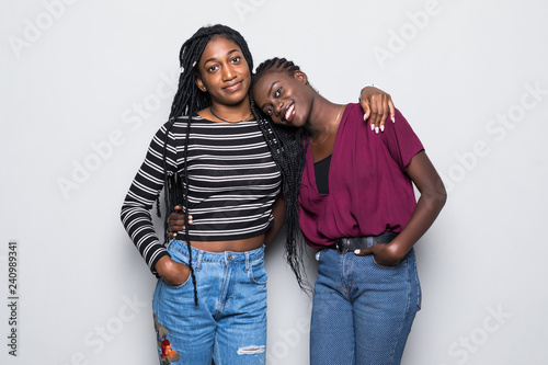 Portrait of two african young women hugging and laughing over white background