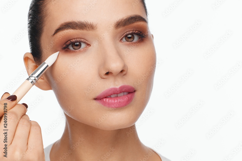 Portrait of a beautiful young woman holding in her hand a white brush for makeup correction