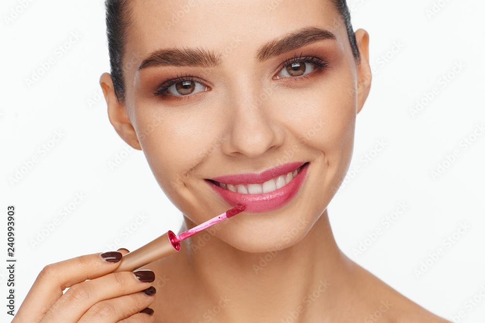Portrait of a beautiful young woman putting lipstick on her lips Portrait of a beautiful young woman putting lipstick on her lips