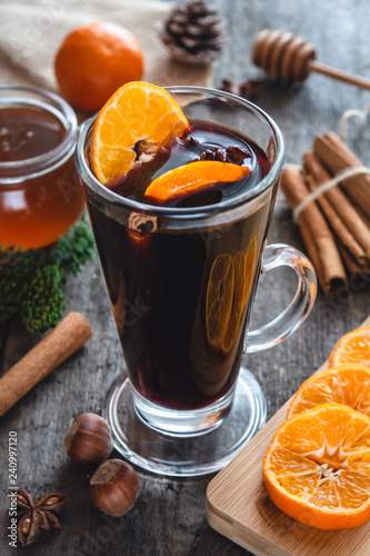 Hot mulled wine with orange, cinnamon, honey and anise on wooden background.