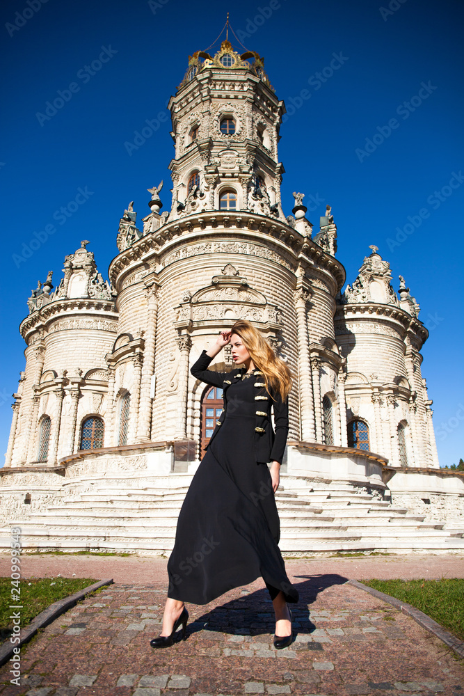 Young woman in black dress on the background of the church