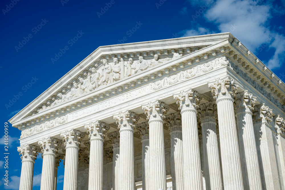 Crisp blue sky view of the neoclassical white marble exterior of the United States Supreme Court Building in Washington DC, USA