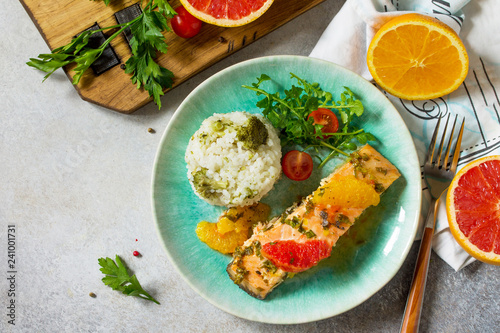 Grilled Salmon with Grapefruit and Orange Sauce and rice garnish on a light stone or concrete table. Top view flat lay background. Copy space.