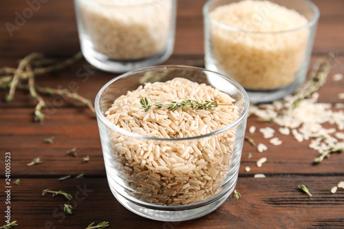 Glass with raw unpolished rice on wooden table