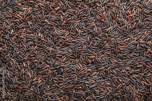 Uncooked black rice as background, top view