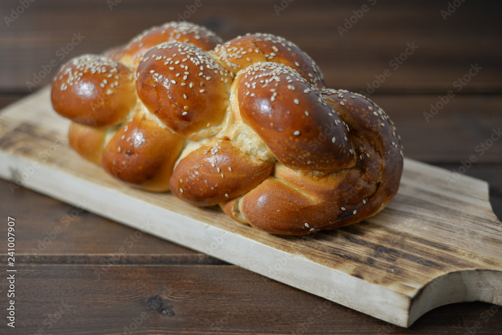 Traditional Jewish sweet Challah bread on a wood plate on wooden table / background with copy space Traditional Jewish sweet Challah bread on a wood plate on wooden table / background with copy space