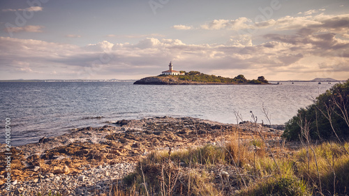 Alcanada Lighthouse (Faro de Alcanada) seen from distance at sunset, color toned picture, Mallorca, Spain. photo