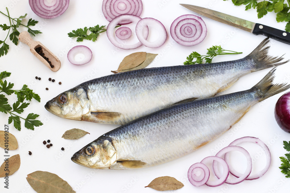 Salted herring with red onion, bay leafs and parsley on the white background, top view Salted herring with red onion, bay leafs and parsley on the white background, top view