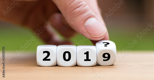 Hand is turning a dice and and changes the year "2019" to "201?" as symbol to the unknown future