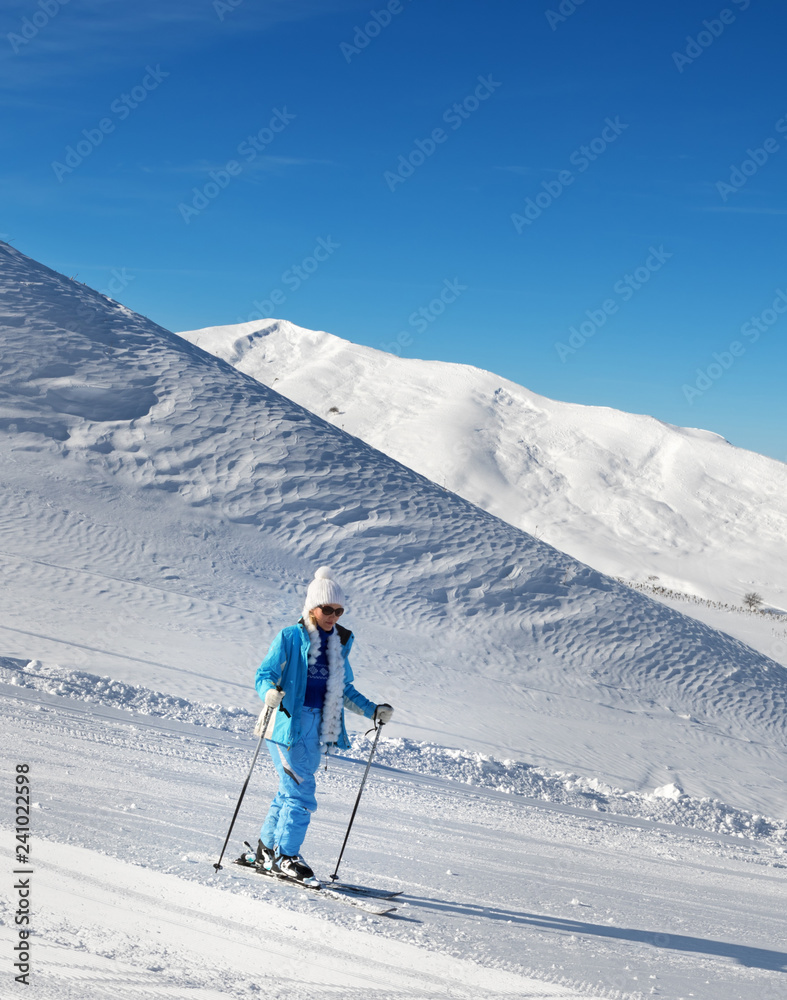 Skier on snowy ski slope at nice sunny day