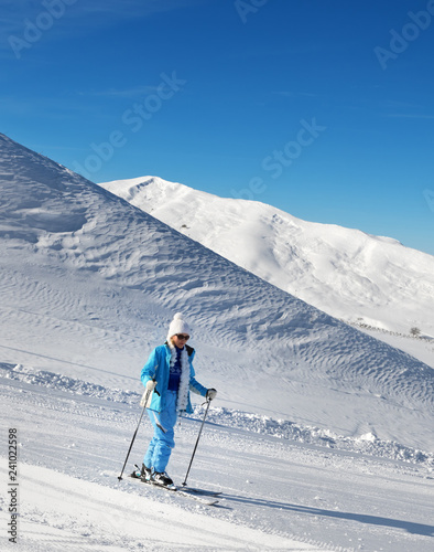 Skier on snowy ski slope at nice sunny day