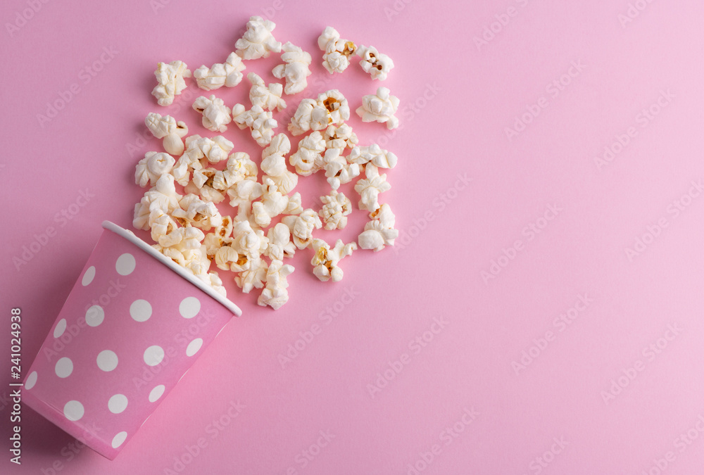Spilled popcorn on a pink background, cinema, movies and entertainment concept Spilled popcorn on a pink background, cinema, movies and entertainment concept