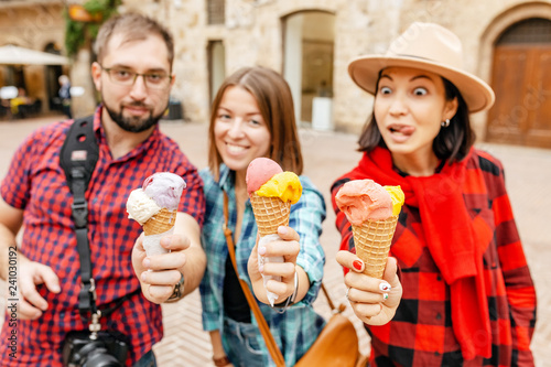 Happy group of friends eating ice-cream in old town center in Italy  travel and food concept