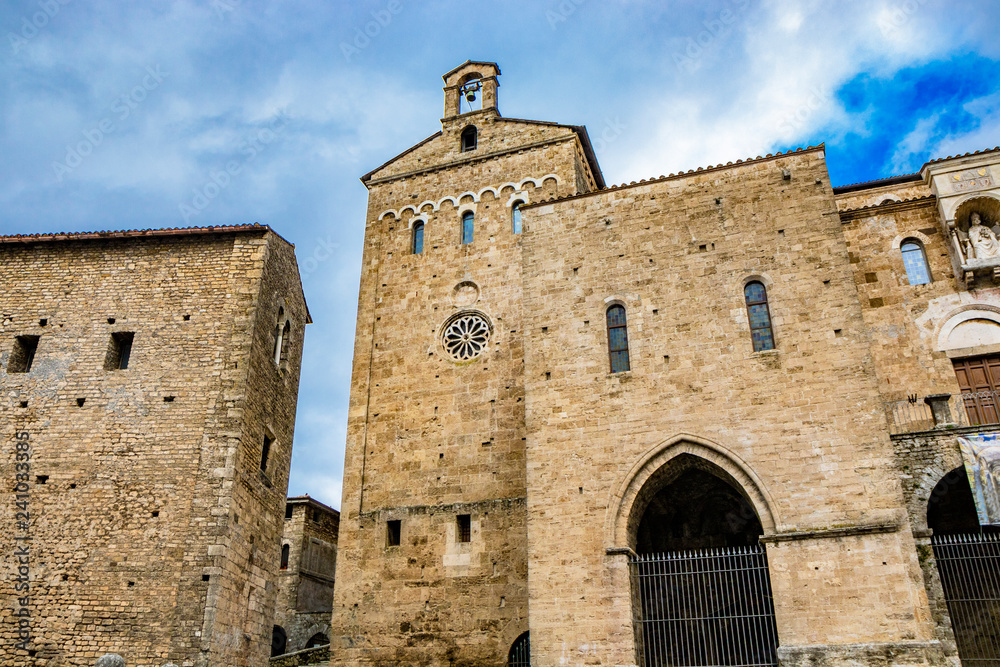 Side facade of the Cathedral Basilica of Santa Maria Annunziata, with the rose window, in Piazza Innocenzo III. Stone buildings from the Middle Ages. Anagni, Frosinone, Italy.