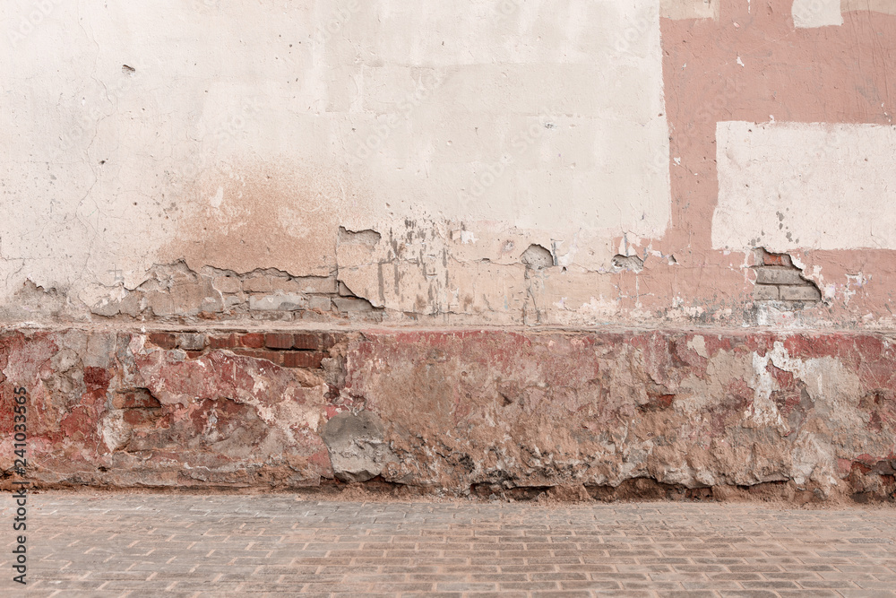 Old dirty damaged wall with cracks, chips, peeling white and pink paint
