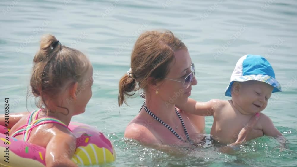 Family mother with two children have the water-based recreation on sea. Happy family lifestyle. Summer travel, water sport outdoor activities, swimming lessons on tropical beach holiday with kids.