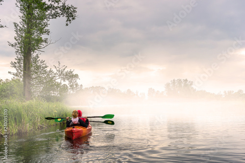 Two girls kayaking in a beautiful morning landscape