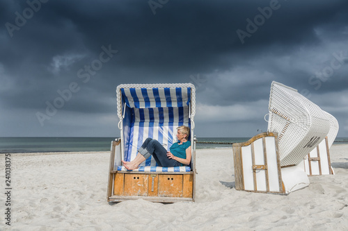 caucasian woman relaxing in strandkorb at baltic sea