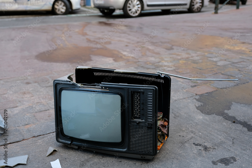 Broken TV set left on a sidewalk