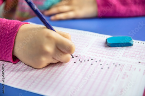 hand student testing in exercise and taking fill in exam carbon paper computer sheet with pencil at school test room, education concept photo