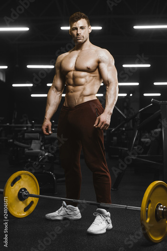 Handsome strong athletic men pumping up muscles workout barbell squat bodybuilding concept background