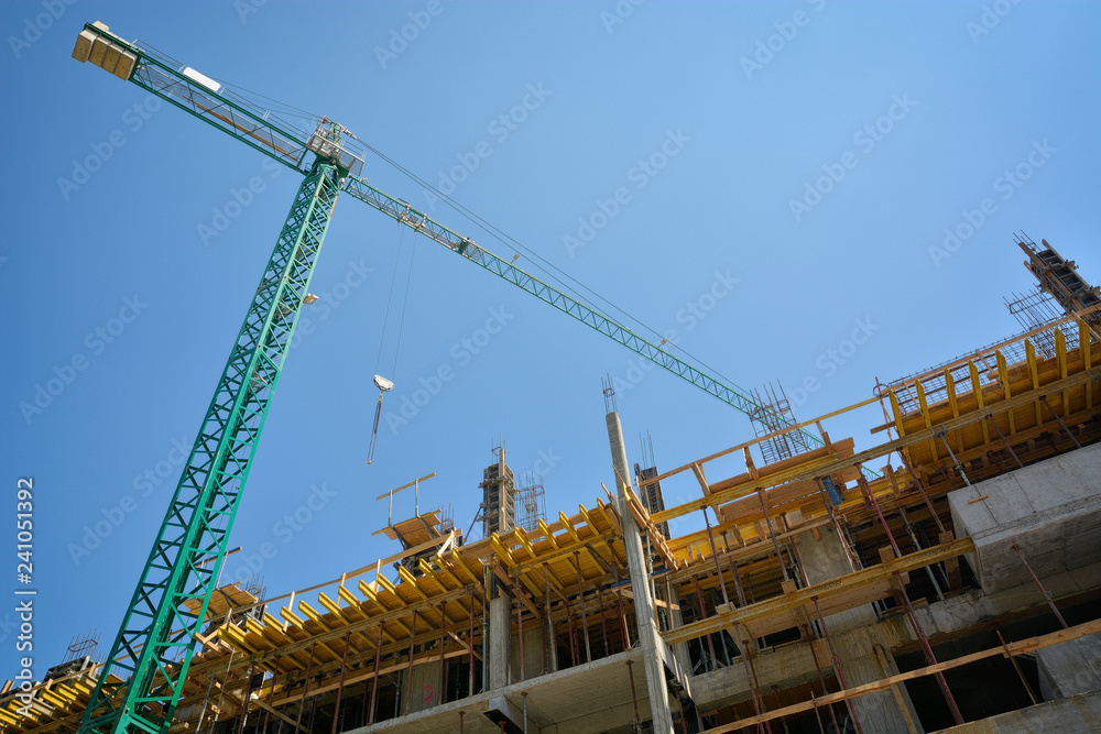 Crane and building construction site against blue sky