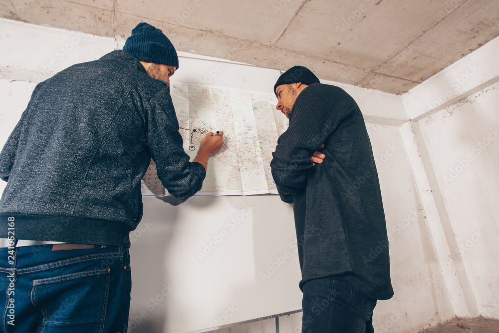 Assaulters making a robbery plan on wall map of the city