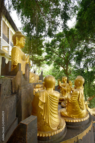 The statue of Buddha sat cross-legged over the lotus flower presenting teachings to his students at Vihara Ratanavana Arama, Lasem, Central Java, Indonesia photo