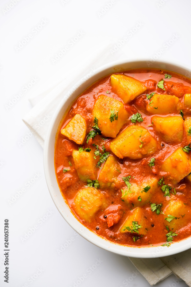 Indian food - Aloo curry masala. Potato cooked with spices and herbs in a tomato curry. served in a bowl over moody background. selective focus