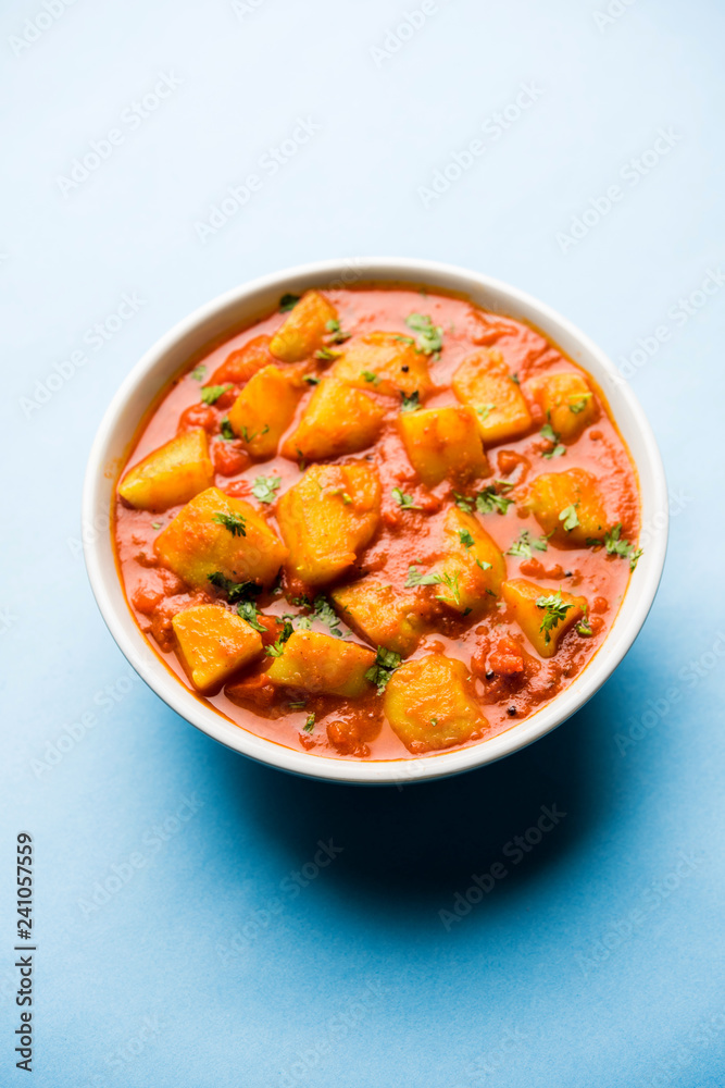 Indian food - Aloo curry masala. Potato cooked with spices and herbs in a tomato curry. served in a bowl over moody background. selective focus Indian food - Aloo curry masala. Potato cooked with spices and herbs in a tomato curry. served in a bowl over moody background. selective focus