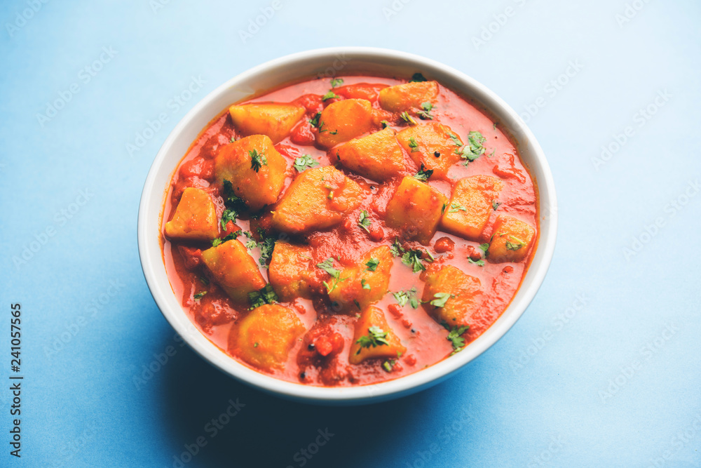Indian food - Aloo curry masala. Potato cooked with spices and herbs in a tomato curry. served in a bowl over moody background. selective focus Indian food - Aloo curry masala. Potato cooked with spices and herbs in a tomato curry. served in a bowl over moody background. selective focus