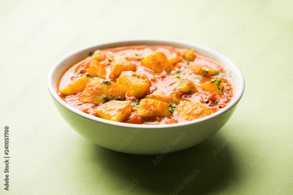 Indian food - Aloo curry masala. Potato cooked with spices and herbs in a tomato curry. served in a bowl over moody background. selective focus Indian food - Aloo curry masala. Potato cooked with spices and herbs in a tomato curry. served in a bowl over moody background. selective focus