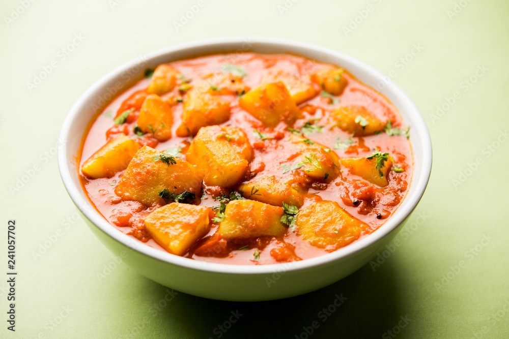 Indian food - Aloo curry masala. Potato cooked with spices and herbs in a tomato curry. served in a bowl over moody background. selective focus Indian food - Aloo curry masala. Potato cooked with spices and herbs in a tomato curry. served in a bowl over moody background. selective focus