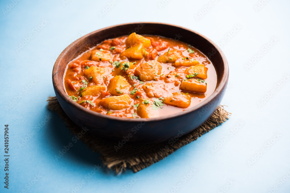 Indian food - Aloo curry masala. Potato cooked with spices and herbs in a tomato curry. served in a bowl over moody background. selective focus Indian food - Aloo curry masala. Potato cooked with spices and herbs in a tomato curry. served in a bowl over moody background. selective focus