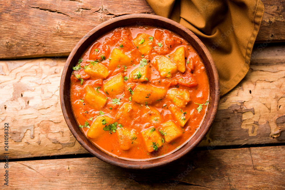 Indian food - Aloo curry masala. Potato cooked with spices and herbs in a tomato curry. served in a bowl over moody background. selective focus - obrazy, fototapety, plakaty 
