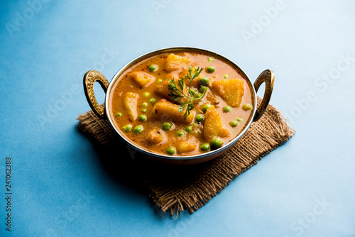 Indian Aloo Mutter curry - Potato and Peas immersed in an Onion Tomato Gravy and garnished with coriander leaves. Served in a Karahi/kadhai or pan or bowl. selective focus photo