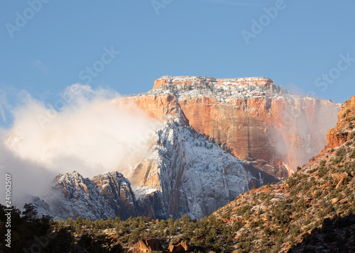 West temple mountain in Zion national park is coated with fresh snow and partially hidden by wispy clouds.