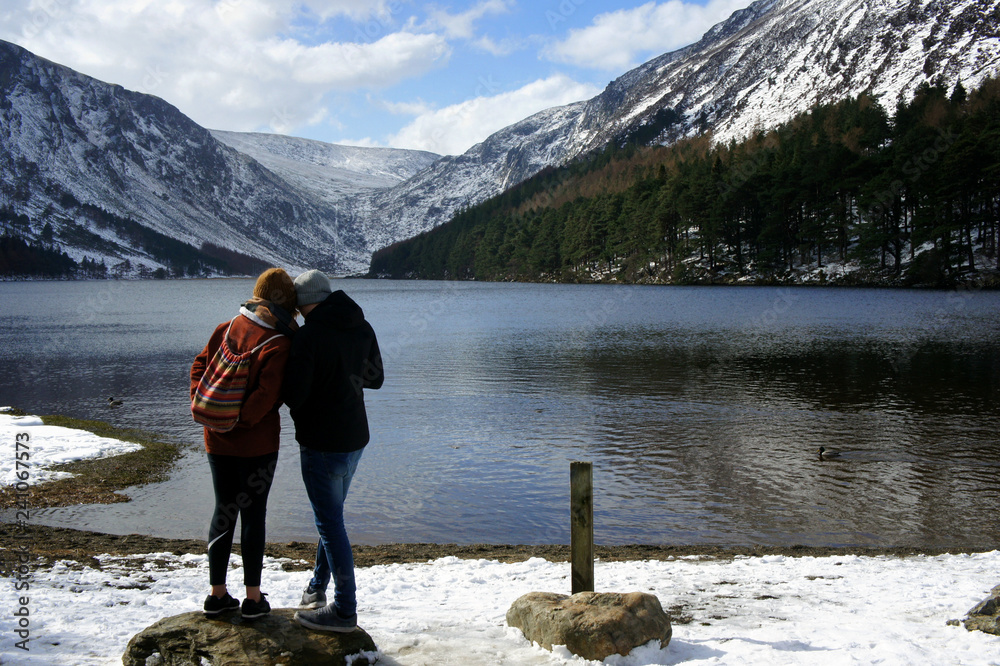 Two people on the shore of the mountain lake.Upper Lake.Glendalough.Wicklow Mountains.Ireland. Two people on the shore of the mountain lake.Upper Lake.Glendalough.Wicklow Mountains.Ireland.