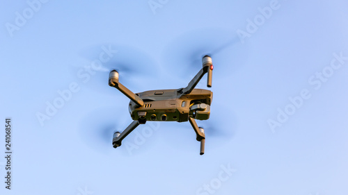 Fototapeta Naklejka Na Ścianę i Meble -  Drone flying over landscape. UAV drone copter flying with digital camera. Drone flying overhead in cloudy blue sky. Quad copter is flying over the  field.