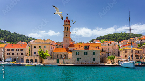 Panorama of picturesque town Pucisca in Croatia, Island Brac, Europe. Pucisca town mediterranean panorama with seagull's flying over the town. Croatia, Island Brac, Europe. photo